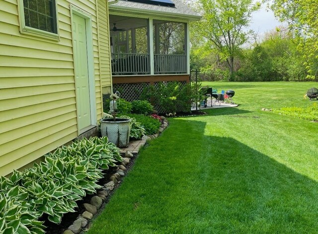 rear view of house featuring a sunroom, a yard, and a patio