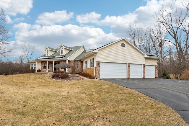 cape cod-style house with driveway, a garage, brick siding, solar panels, and a front yard