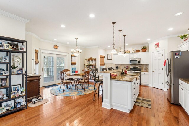 kitchen with light wood-style flooring, a sink, white cabinetry, appliances with stainless steel finishes, and decorative backsplash