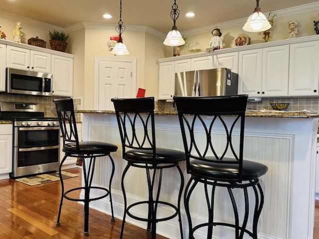 kitchen with a kitchen breakfast bar, stainless steel appliances, and white cabinetry