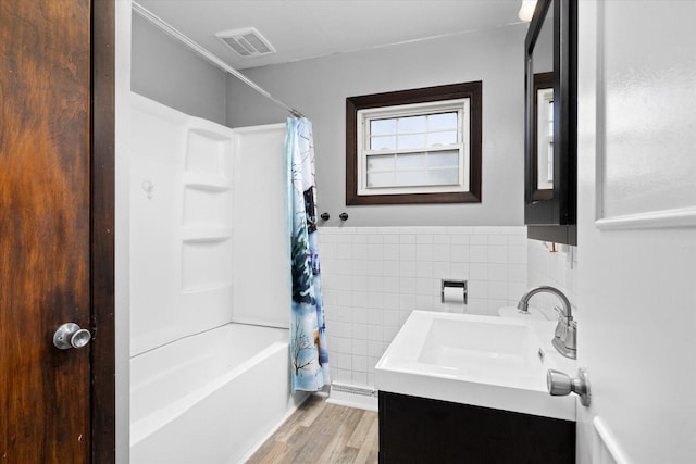 bathroom with tile walls, vanity, hardwood / wood-style flooring, and shower / bath combo