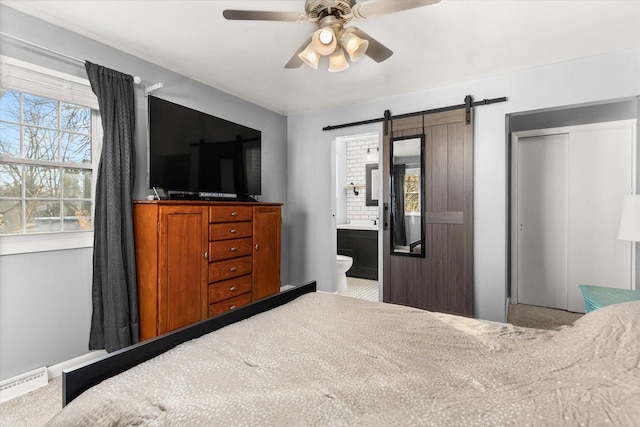 bedroom featuring a barn door, connected bathroom, ceiling fan, and a closet