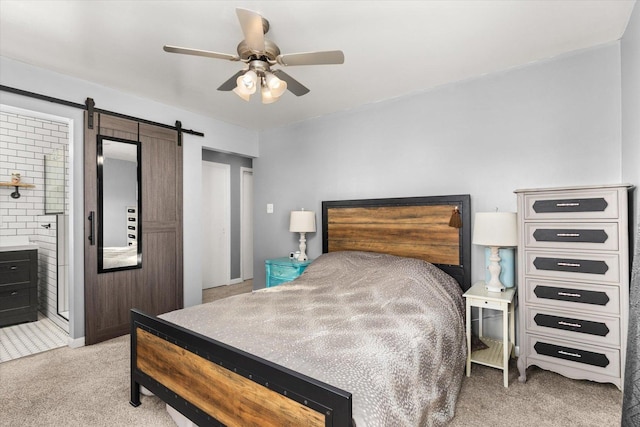 bedroom with ceiling fan, a barn door, light carpet, and ensuite bath