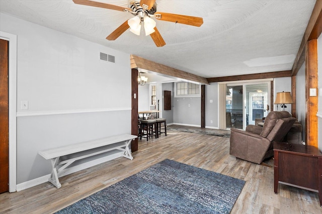 living room featuring wood-type flooring, ceiling fan with notable chandelier, and a textured ceiling