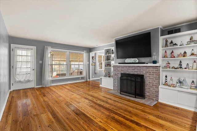 unfurnished living room featuring a fireplace, light hardwood / wood-style floors, and built in features