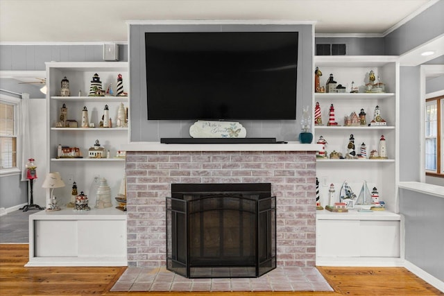 living room with a fireplace, crown molding, wood-type flooring, and built in features