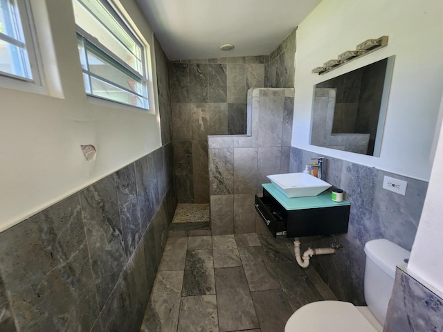 bathroom with toilet, tile walls, walk in shower, and vanity