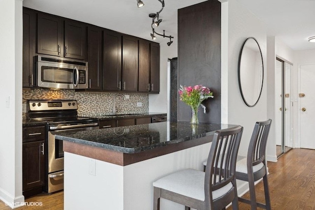 kitchen with dark stone countertops, sink, decorative backsplash, and appliances with stainless steel finishes