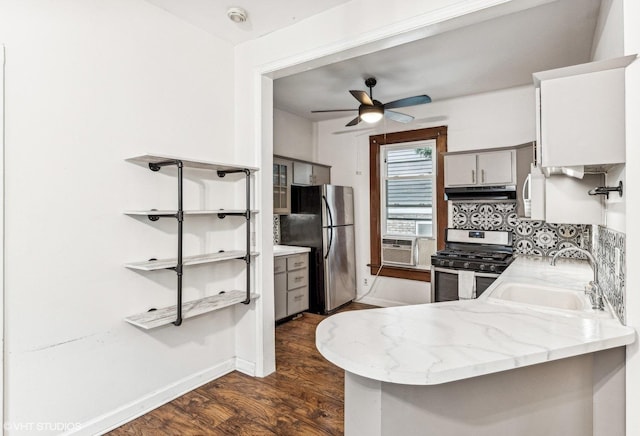 kitchen with appliances with stainless steel finishes, dark wood-type flooring, sink, backsplash, and kitchen peninsula