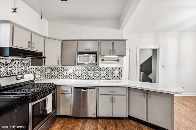 kitchen featuring tasteful backsplash, gray cabinets, kitchen peninsula, sink, and appliances with stainless steel finishes