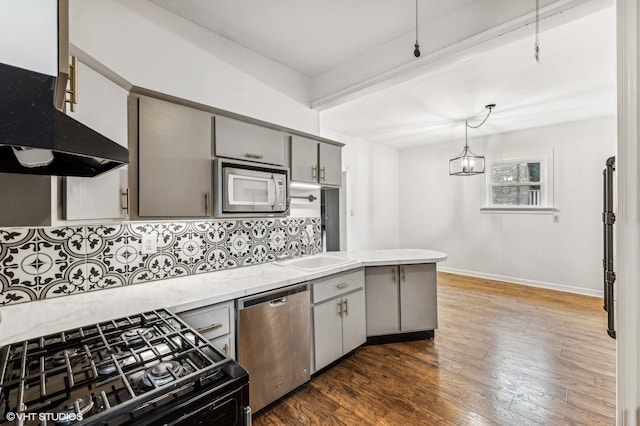 kitchen featuring stainless steel appliances, gray cabinetry, backsplash, dark wood-type flooring, and pendant lighting