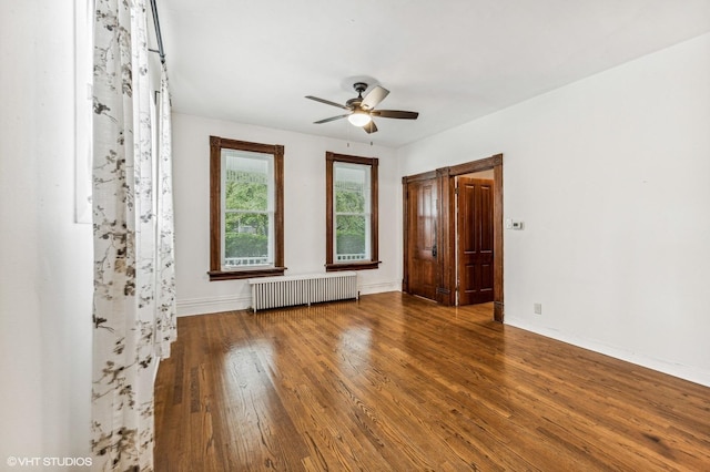 empty room featuring ceiling fan, wood-type flooring, and radiator heating unit