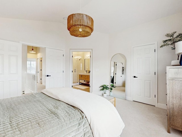 carpeted bedroom featuring vaulted ceiling and connected bathroom