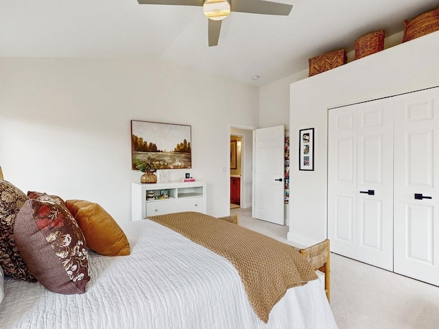 bedroom with vaulted ceiling, light colored carpet, ceiling fan, and a closet