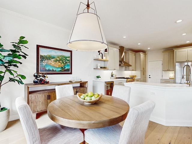 dining space featuring ornamental molding, sink, wine cooler, and light wood-type flooring