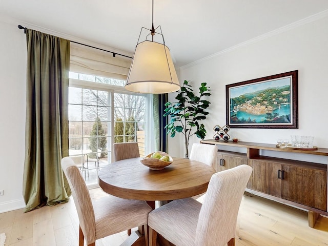 dining area featuring ornamental molding and light hardwood / wood-style flooring