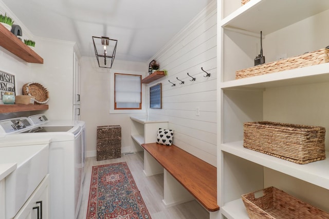 laundry room featuring light wood-type flooring, crown molding, wooden walls, and washer and dryer