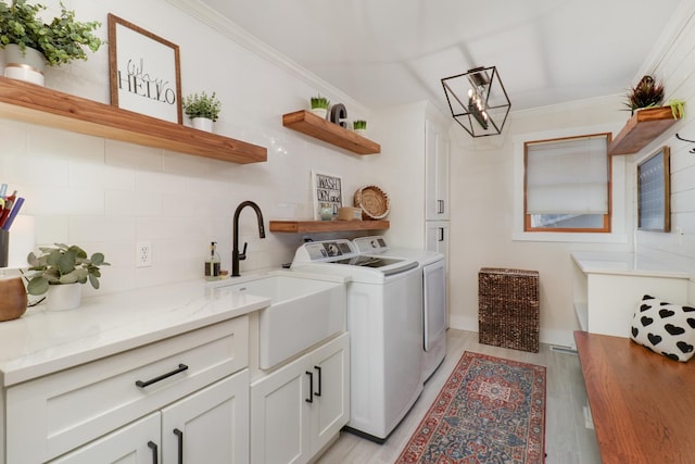 washroom featuring light hardwood / wood-style flooring, sink, washer and dryer, cabinets, and ornamental molding