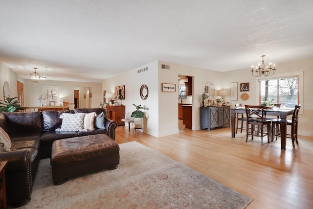 living room with an inviting chandelier and light wood-type flooring