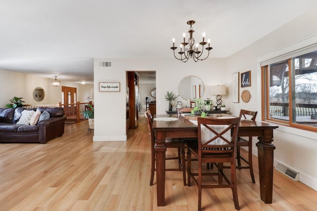 dining space with an inviting chandelier and light hardwood / wood-style flooring