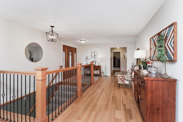 hall featuring light wood-type flooring and a notable chandelier