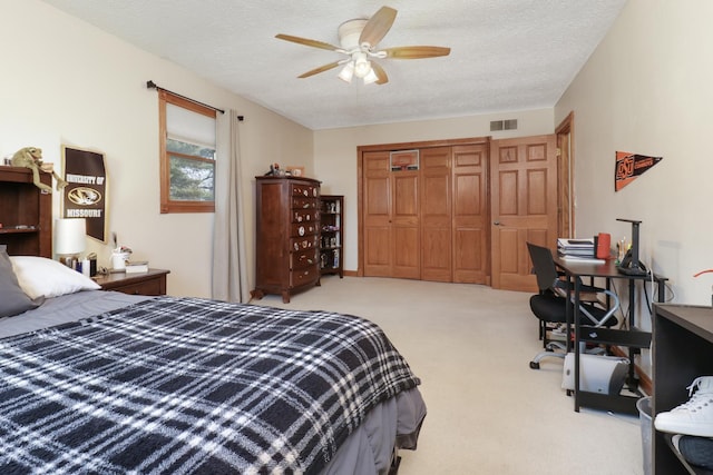 carpeted bedroom with ceiling fan, a textured ceiling, and a closet