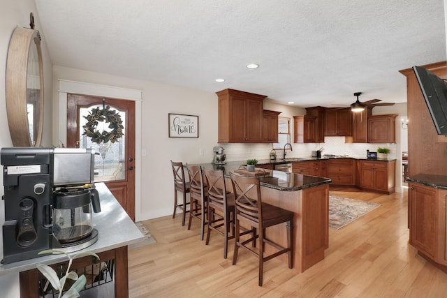 kitchen with kitchen peninsula, light hardwood / wood-style flooring, sink, tasteful backsplash, and a kitchen bar