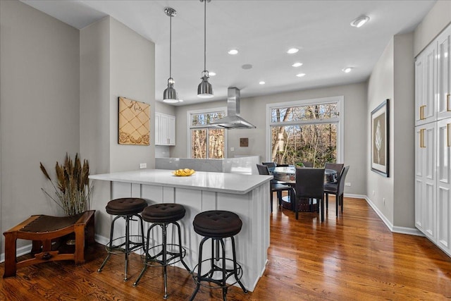 kitchen featuring pendant lighting, island range hood, white cabinets, and kitchen peninsula