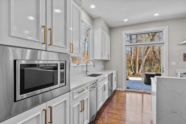 kitchen featuring dark wood-type flooring, sink, white cabinetry, stainless steel appliances, and light stone countertops