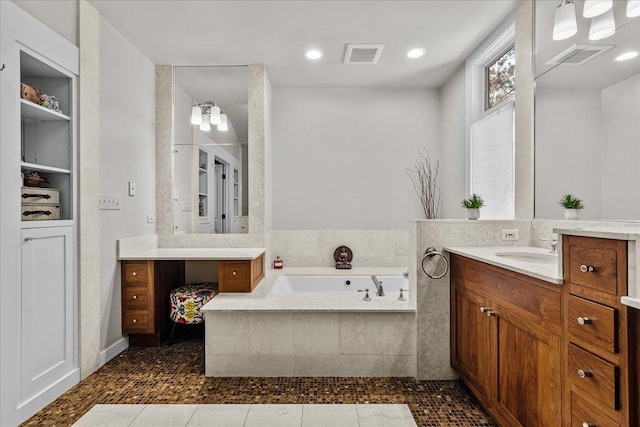 bathroom with tile patterned flooring, vanity, and tiled bath