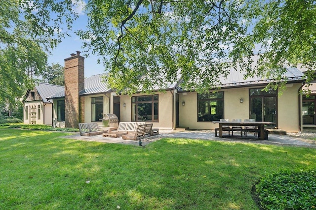 back of property featuring a yard, a patio, and a fire pit