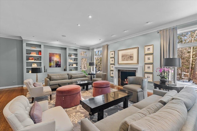 living room featuring ornamental molding, wood-type flooring, a fireplace, and a wealth of natural light