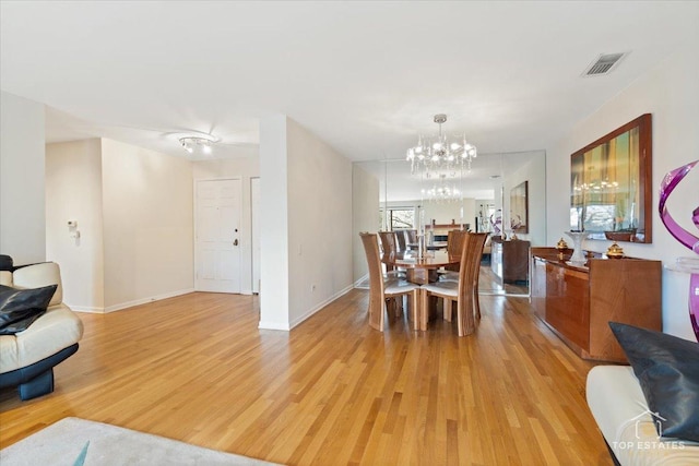 dining space with a notable chandelier and light hardwood / wood-style flooring