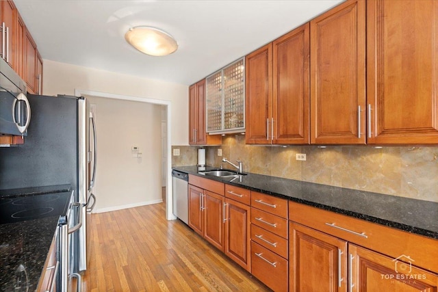 kitchen with dark stone countertops, sink, stainless steel appliances, and light wood-type flooring