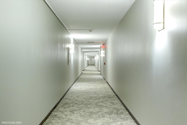 corridor featuring light colored carpet and a textured ceiling