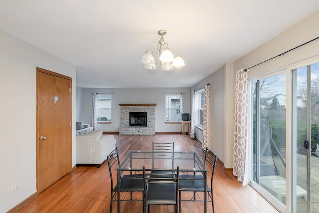 dining area featuring light hardwood / wood-style floors, a fireplace, and a notable chandelier