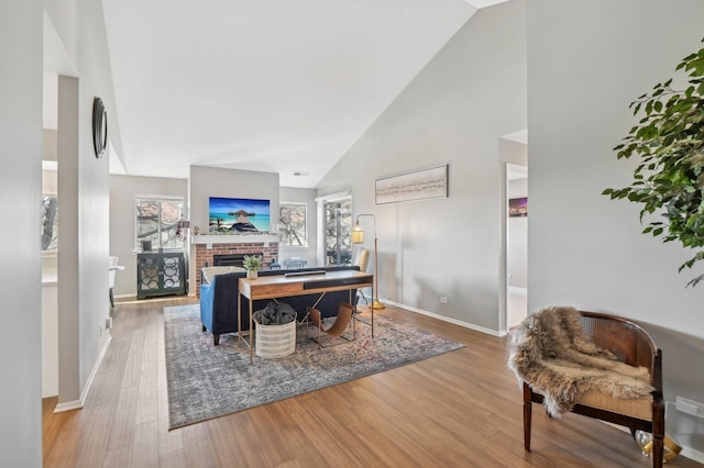 office with high vaulted ceiling, a fireplace, and light hardwood / wood-style floors