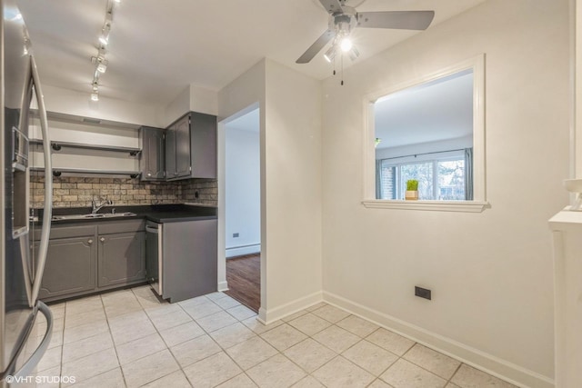 kitchen featuring light tile patterned flooring, sink, baseboard heating, and decorative backsplash