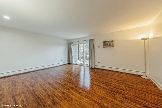 empty room featuring a wall mounted AC, hardwood / wood-style floors, and baseboard heating