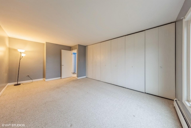 unfurnished bedroom featuring a baseboard heating unit and light colored carpet