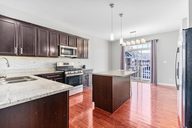 kitchen with a kitchen island, appliances with stainless steel finishes, sink, backsplash, and light stone counters