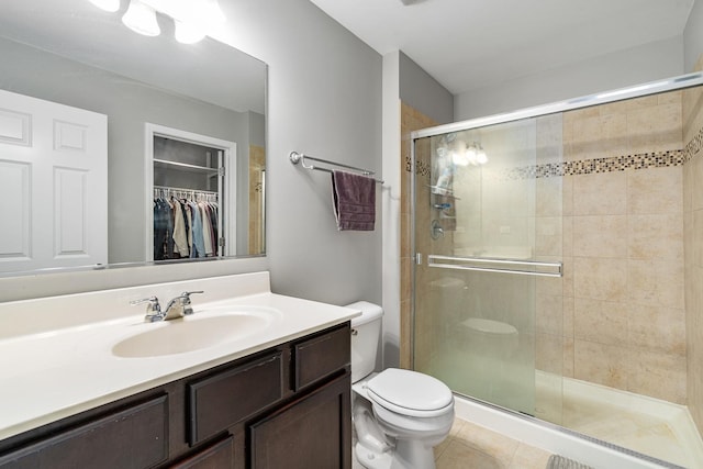 bathroom with tile patterned floors, vanity, toilet, and a shower with shower door