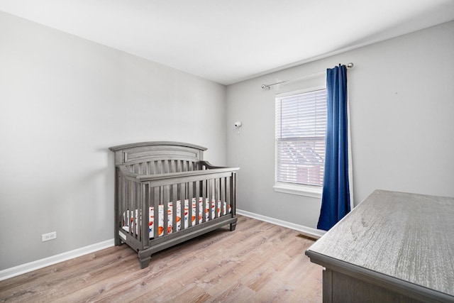 bedroom featuring a nursery area and light wood-type flooring