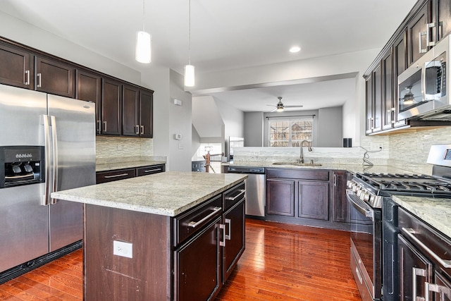 kitchen featuring pendant lighting, sink, appliances with stainless steel finishes, backsplash, and a center island