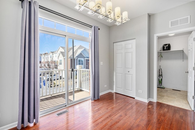 unfurnished bedroom with an inviting chandelier, hardwood / wood-style floors, and a closet