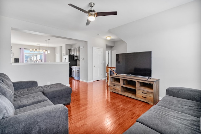 living room featuring hardwood / wood-style flooring and ceiling fan with notable chandelier