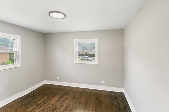 unfurnished room with a baseboard radiator, dark wood-type flooring, and a wealth of natural light