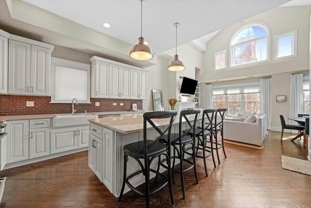 kitchen featuring a center island, decorative backsplash, a kitchen breakfast bar, sink, and white cabinets