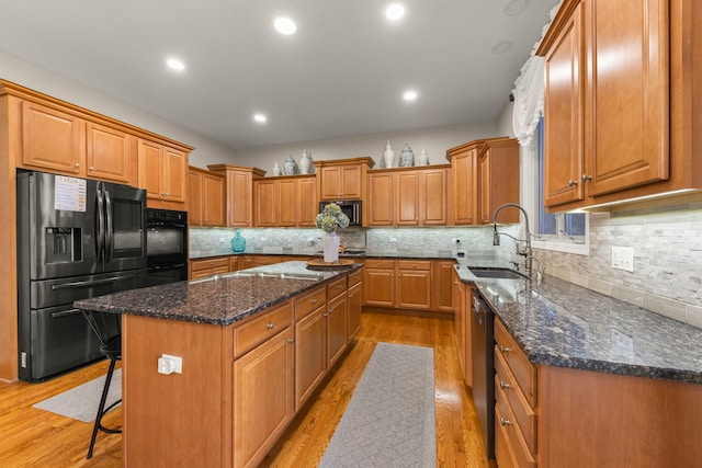 kitchen featuring appliances with stainless steel finishes, a center island, sink, and dark stone countertops