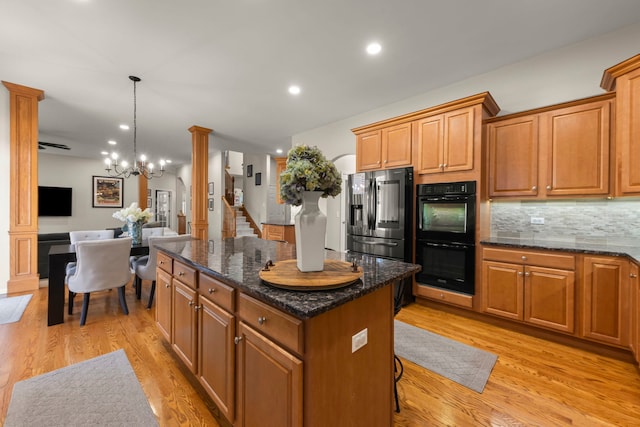 kitchen featuring a center island, stainless steel fridge with ice dispenser, dark stone countertops, pendant lighting, and black double oven